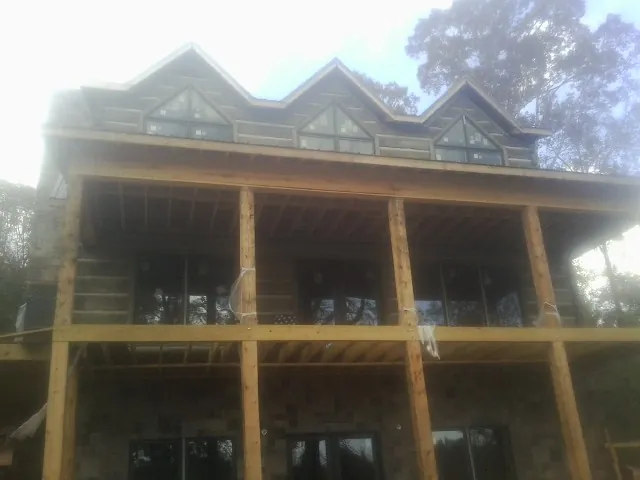 Dormers and porch framing on a large log home under construction — Roof Coating work by our crew in Mont Clare