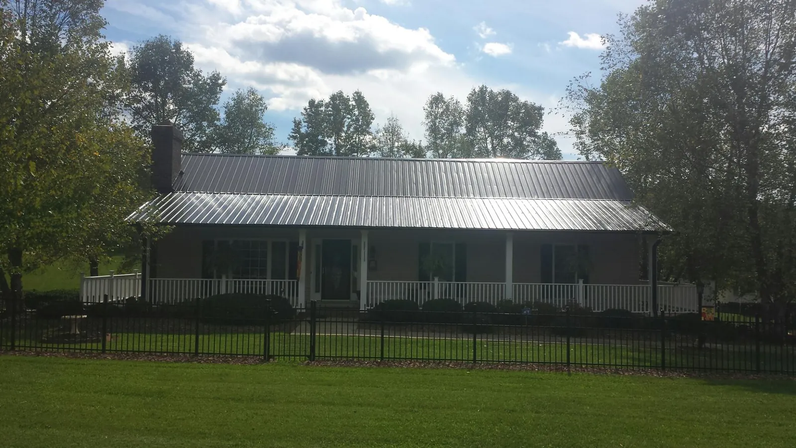 Gray metal roof on a brick ranch with a full width front porch — Gutter Guard Installation work by our crew in Mont Clare