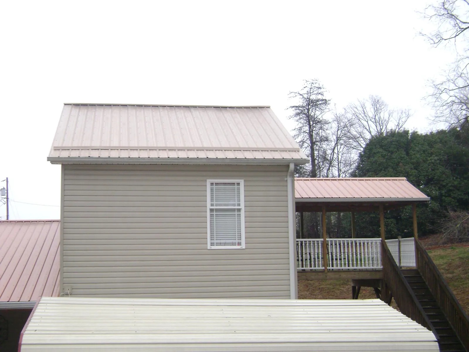 Tan metal roofs on a two story addition and attached porch, from a Roof Replacement job in Mont Clare