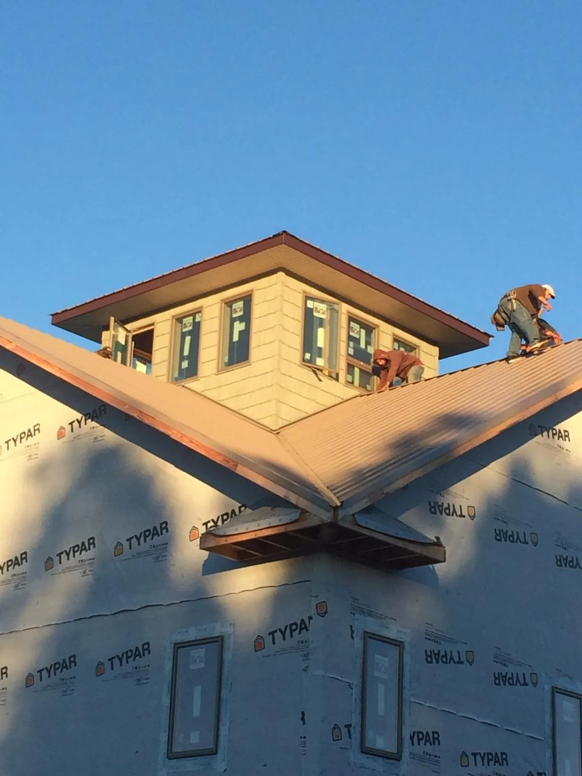 Roofers working around a rooftop cupola on a new metal roof at sunset — Roof Waterproofing in Mont Clare by Roofing Brothers